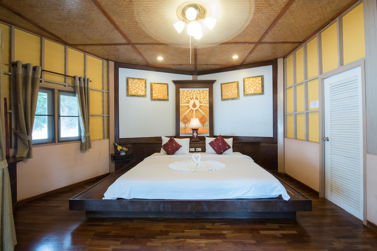 Un dormitorio amplio con una cama grande, suelo de madera y un ventilador de techo.