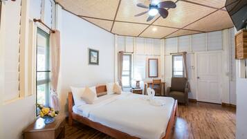 A spacious bedroom with a large bed, a wooden ceiling, a ceiling fan, and a desk with a chair.