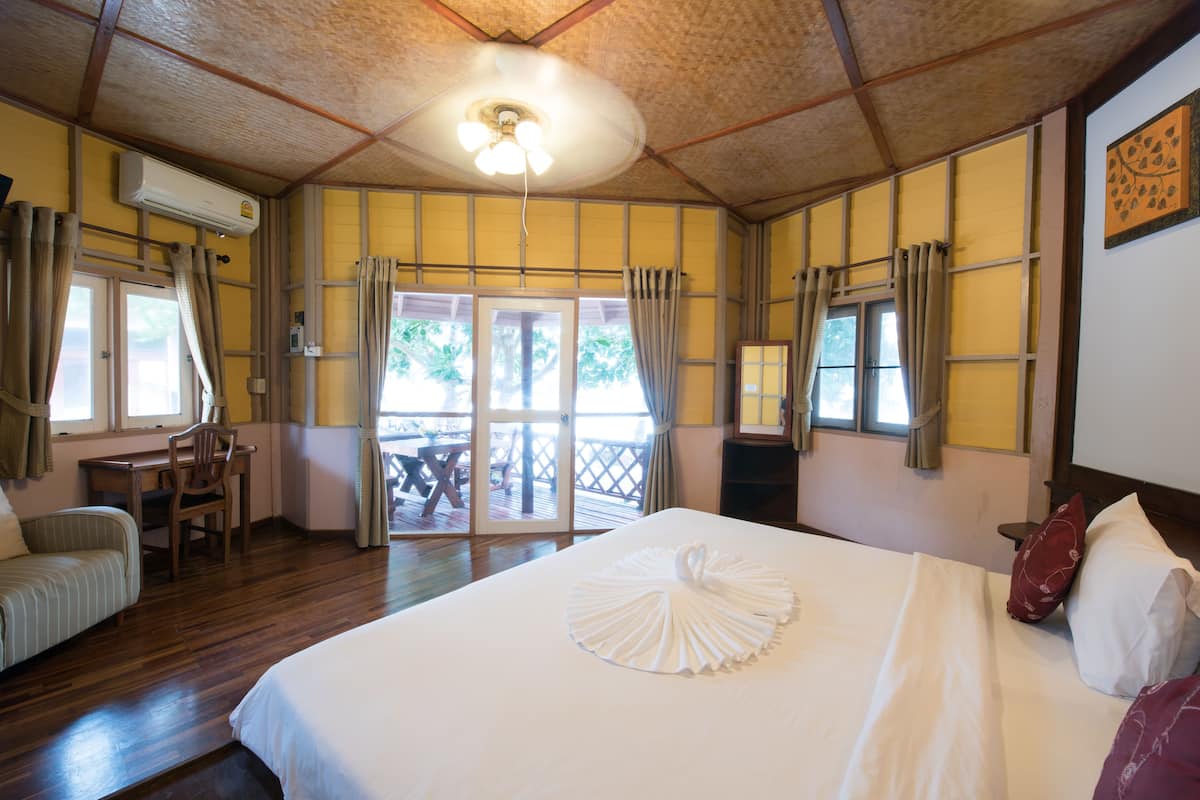 Habitación de hotel con cama, escritorio y silla. Posee un ventanal corredera que da a un espacio al aire libre.