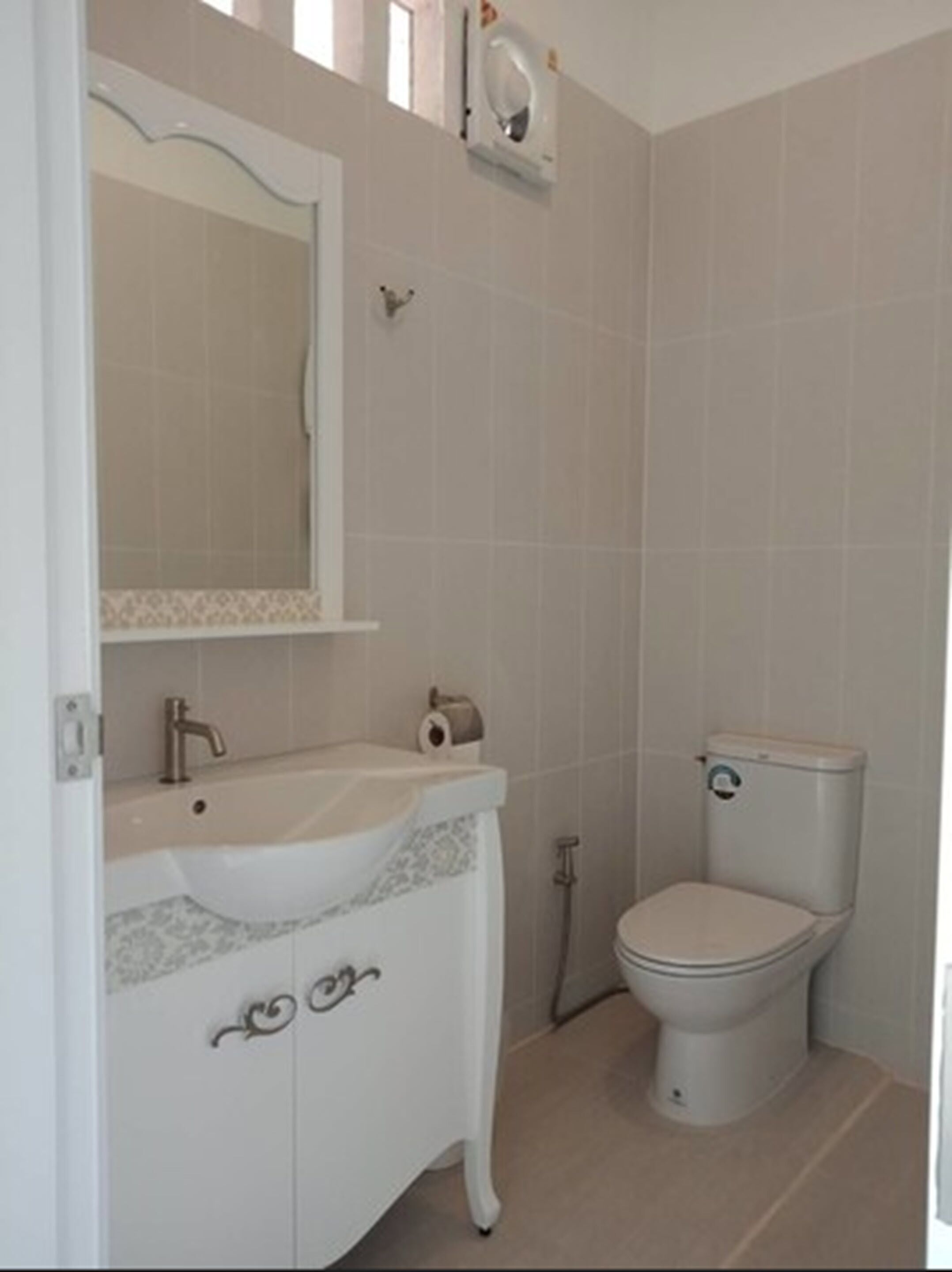 A bathroom with a white sink, mirror, toilet, and a shower area.