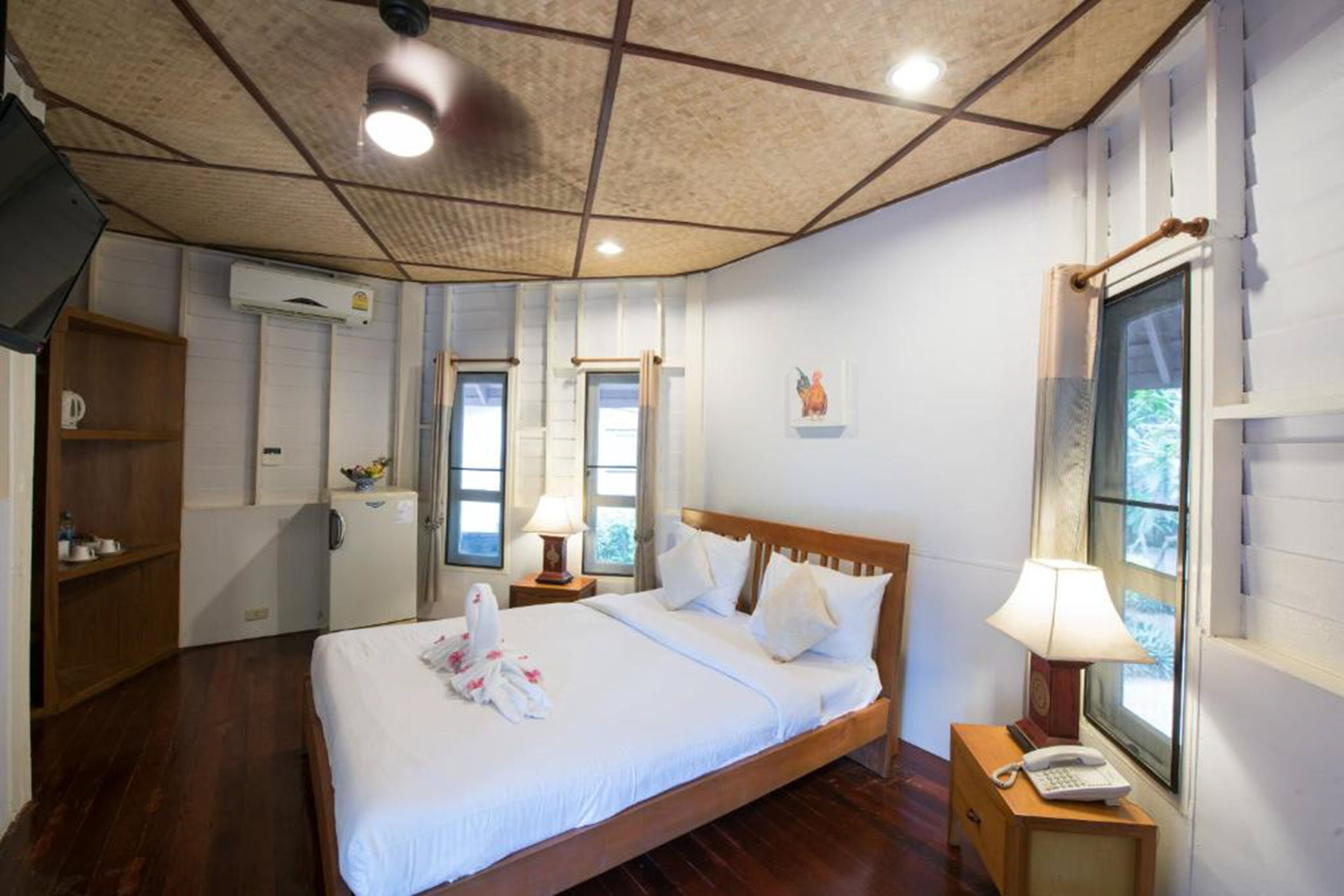 A hotel room with a wooden bed, a desk with a lamp, a wardrobe, and a window with a view.