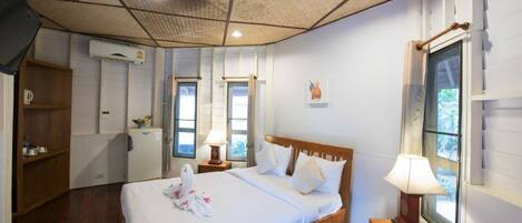 A hotel room with a wooden bed, a desk with a lamp, a wardrobe, and a window with a view.