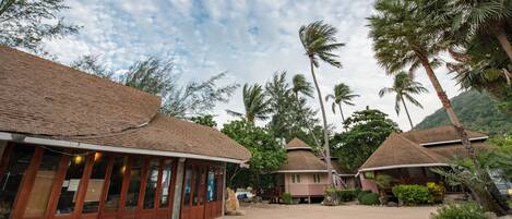 Un resort con varias edificaciones tipo bungalow, un camino pavimentado y palmeras.