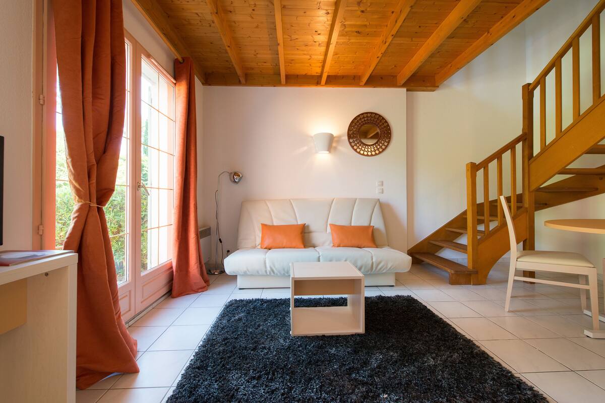 A living room with a sofa, a small table, and a staircase.