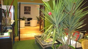 A reception area with a reception desk, chairs, a plant, and a door leading to a waiting area.