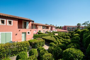 A row of pink buildings with balconies, surrounded by well-maintained hedges. - Adonis Mouans-sartoux L'Albatros (Mouans-Sartoux)