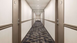 A hotel hallway with carpeted floors, doors on both sides, and a ceiling with recessed lighting. - Super 8 by Wyndham Sarnia ON (Sarnia)