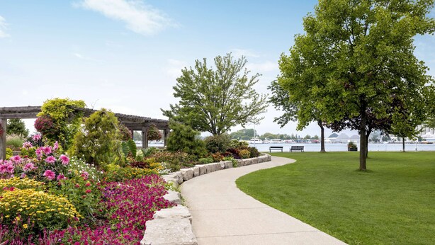 A landscaped garden with a curved walkway, benches, and a pergola. - Super 8 by Wyndham Sarnia ON (Sarnia)