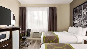 A hotel room with a bed, a desk with a microwave, a chair, and a large window with curtains.