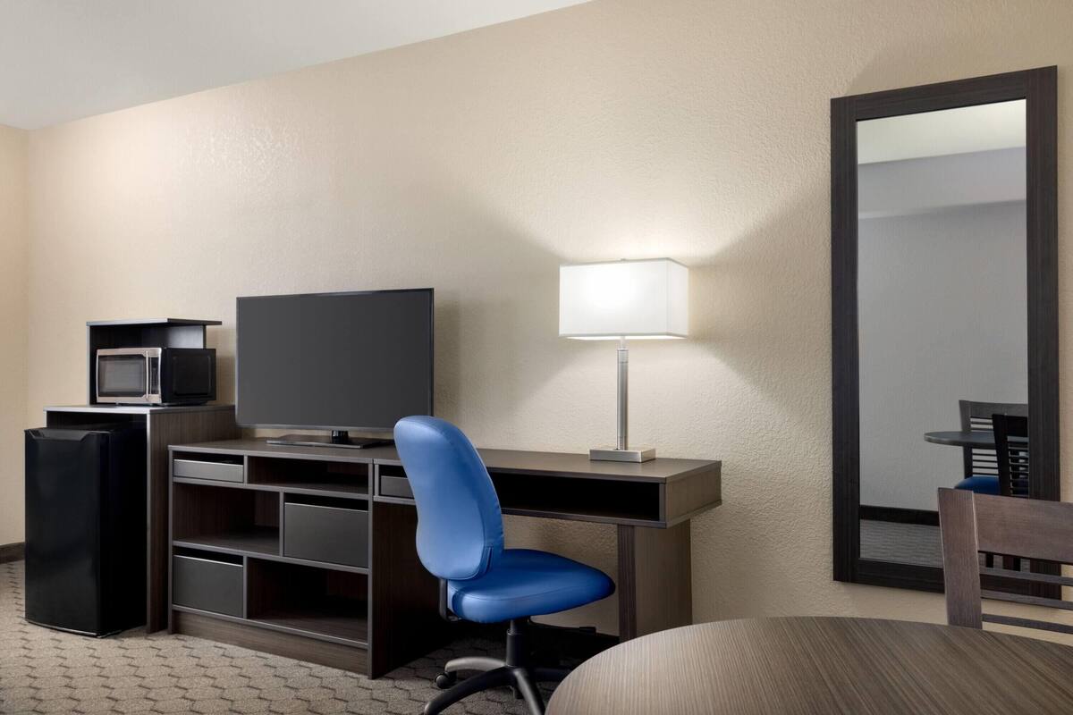 Une chambre d’hôtel équipée d’un bureau, d’une télévision, d’une lampe, d’une chaise et d’un réfrigérateur.