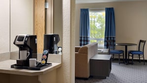 Een hotelkamer met koffiezetapparaat, een bank, een eettafel en stoelen.