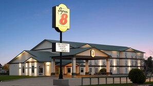 Een hotel met een groot bord waarop 'Super 8 by Wyndham' staat, en een verwelkomend bord met de tekst 'Je verdient het beste verblijf bij Super 8'.