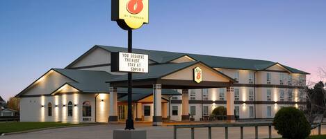 A hotel with a prominent 'Super 8' sign, a welcoming entrance, and a sign stating 'You deserve the best stay at Super 8'.