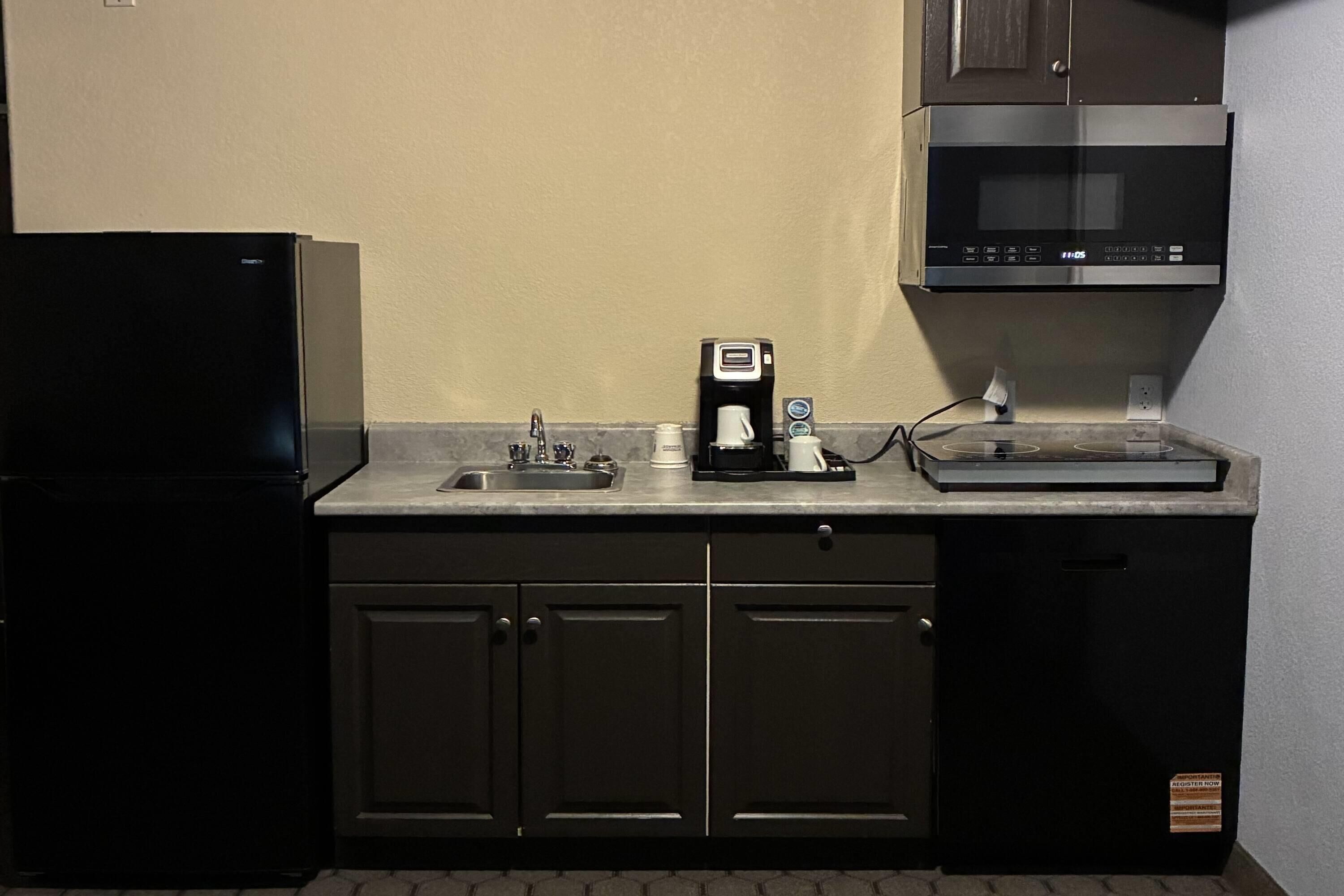 A kitchen with a refrigerator, coffee maker, microwave, and dishwasher.