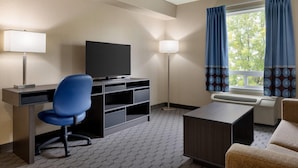 Een hotelkamer met een bureau, stoel, televisie en een raam met gordijnen.
