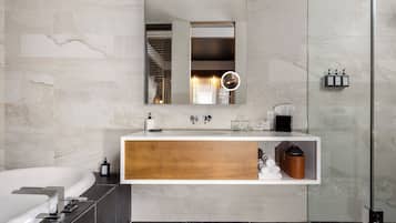 Un baño moderno con un espejo grande, un tocador de madera, una bañera y una zona de ducha.