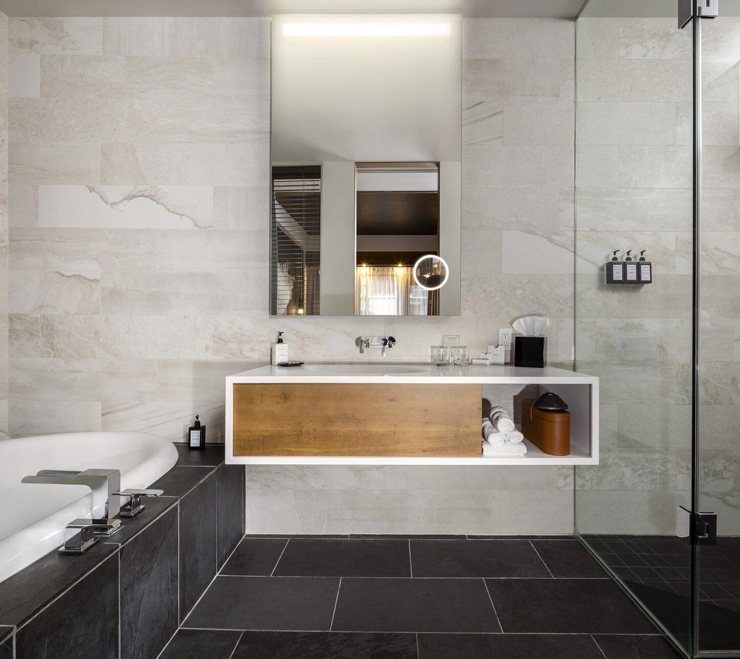 A modern bathroom with a large mirror, a built-in sink, a bathtub, and a shower area.