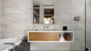 A modern bathroom with a large mirror, a built-in sink, a bathtub, and a shower area.