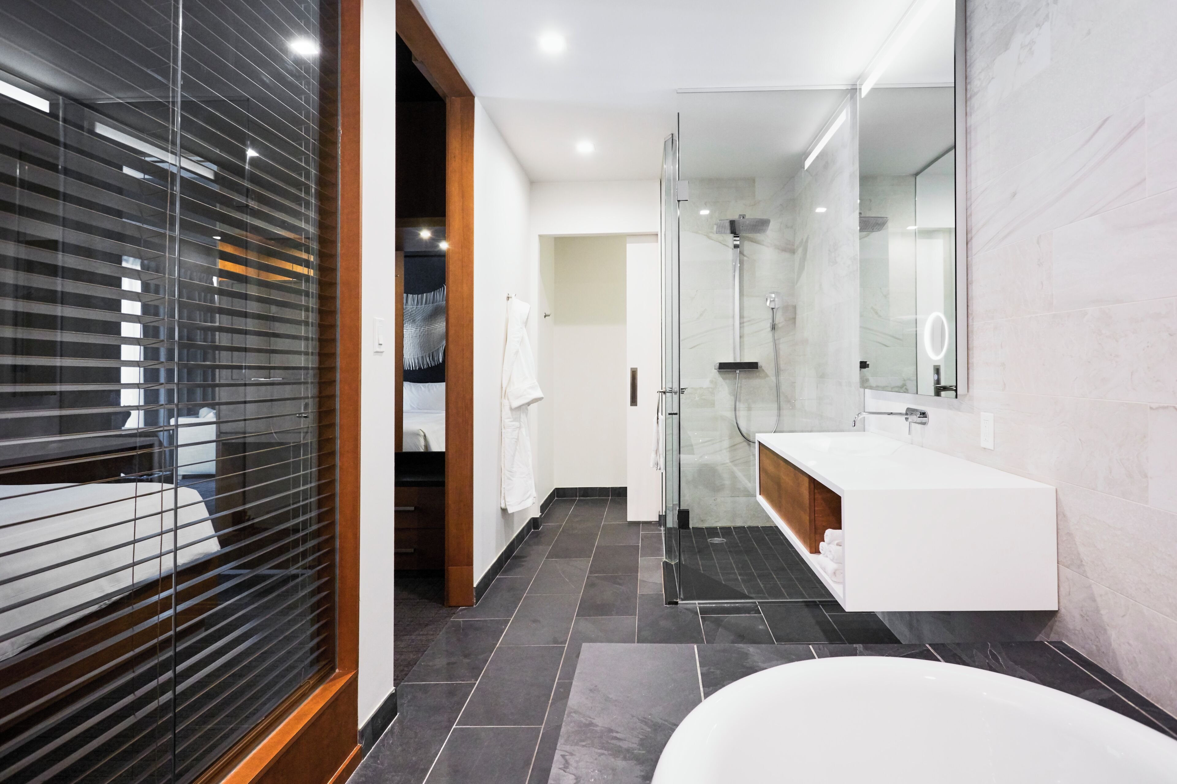 Un baño moderno con cabina de ducha de vidrio, un lavamanos blanco y un espejo grande.