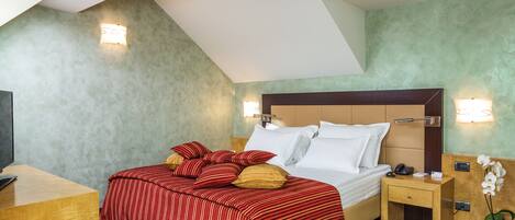 A hotel room with a bed, bedside tables, a desk, and a TV.