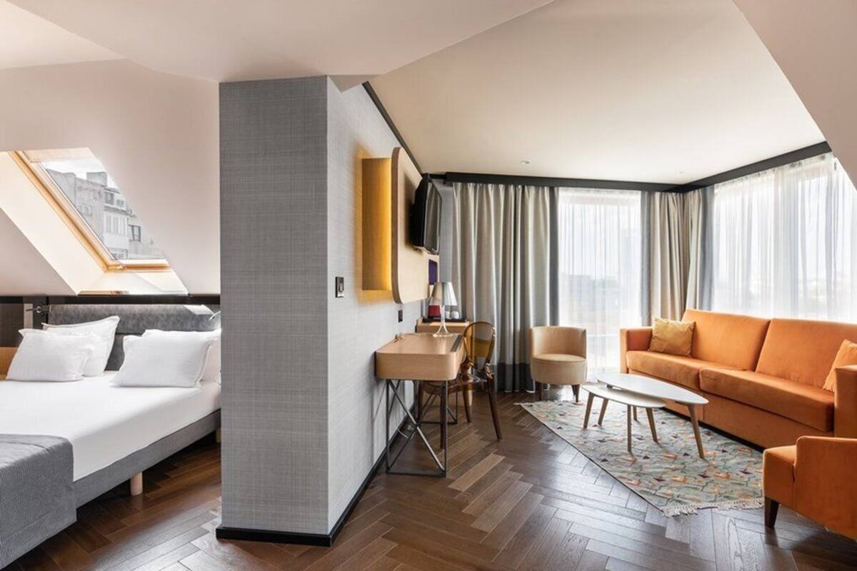 Hotelkamer met een bed, een bank, een salontafel, een televisie en een bureau met stoel.