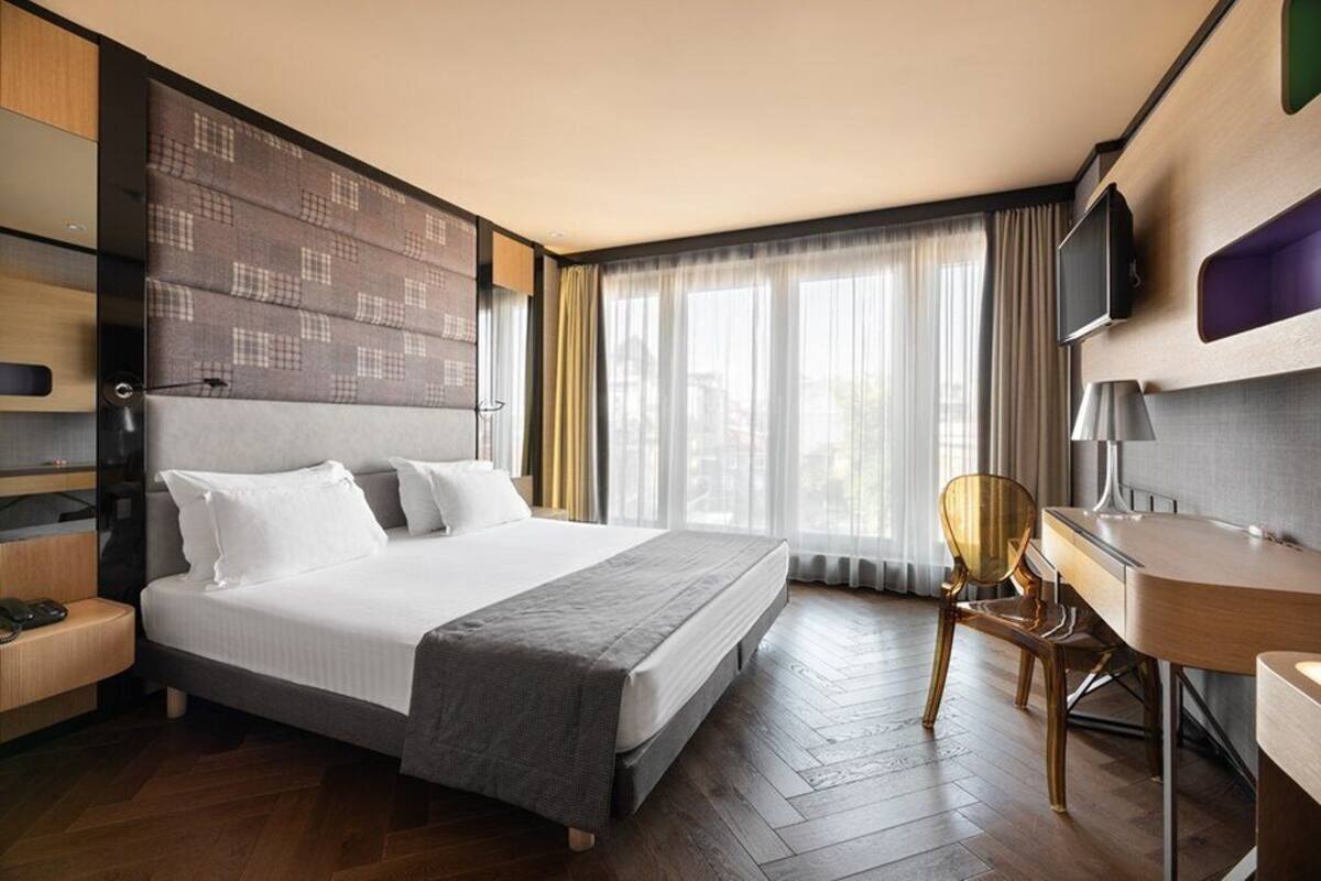 Een moderne hotelkamer met een groot bed, een bureau en een stoel.