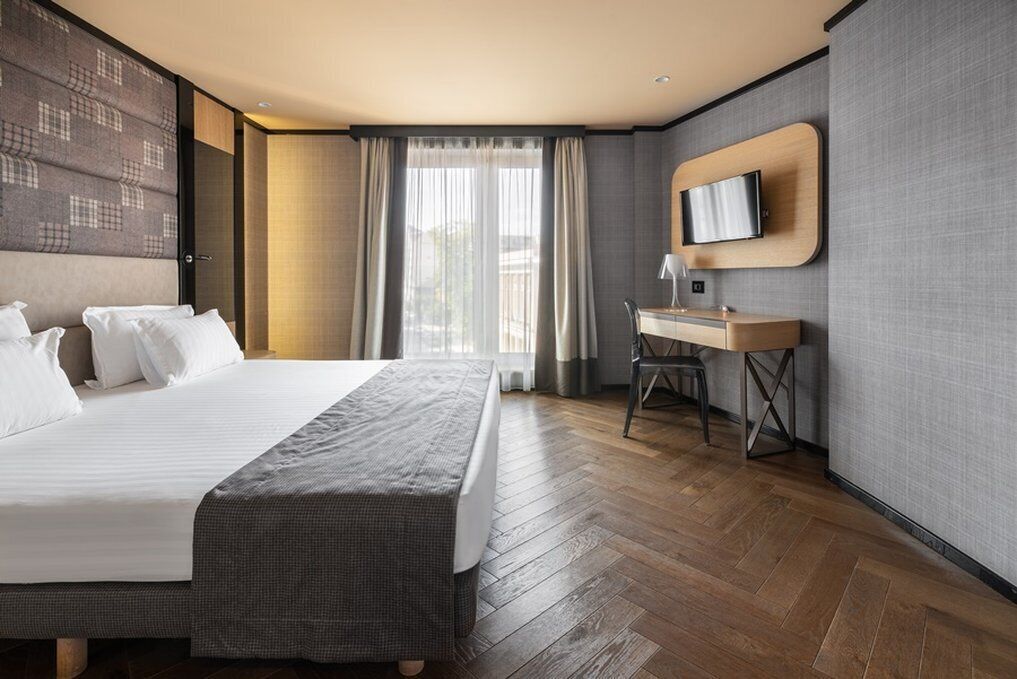 A modern hotel room with a large bed, a desk, and a television.