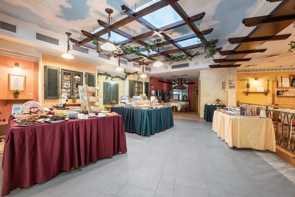 A spacious room with a high ceiling, wooden beams, and a skylight. Tables are set up with various food items and a buffet setup.