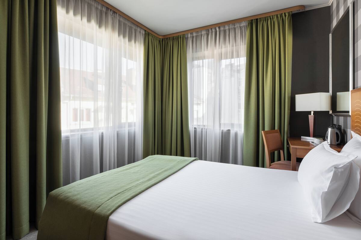 Een hotelkamer met een bed, een stoel, een tafel en een lamp.