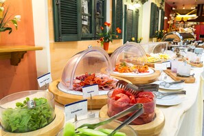Ein Buffet mit abgegrenzten Bereichen für Wurstwaren, Tomaten, Gurken und weiteres Gemüse.