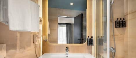 A modern bathroom with a large mirror, a sink, and a shower.