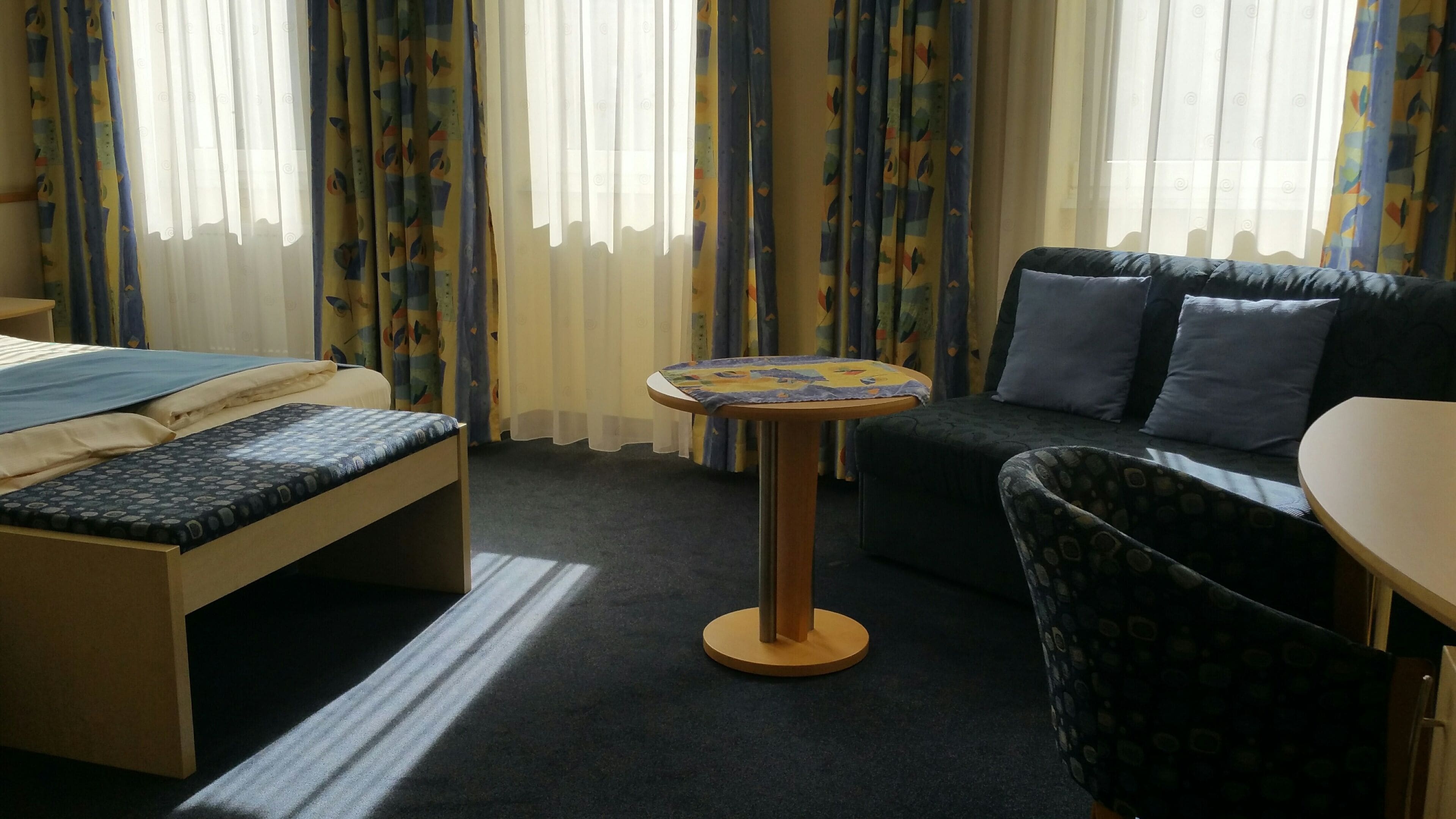 Una habitación de hotel con una cama, un sofá, una mesita redonda y una silla.