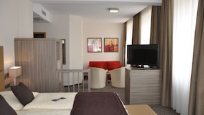 Une chambre d’hôtel avec deux lits, une télévision, un bureau et un canapé rouge.