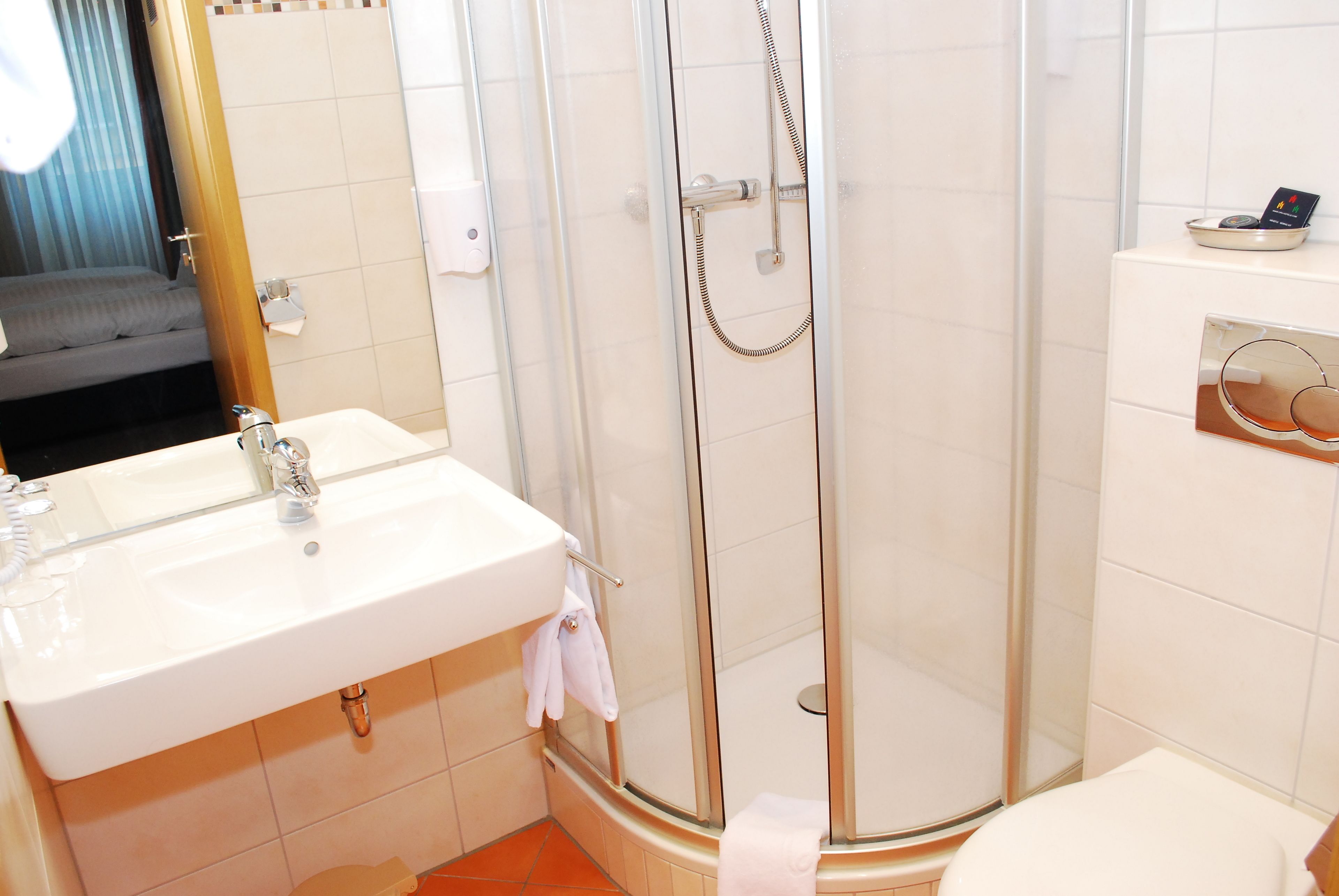 A bathroom with a glass-enclosed shower, a sink with a mirror, and a toilet.