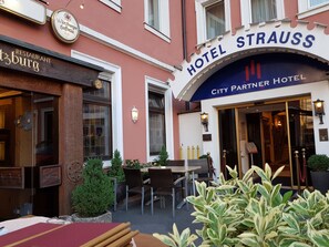 En hotellentrén med en skylt som visar texten: ”Hotel Strauss City Partner Hotel”.