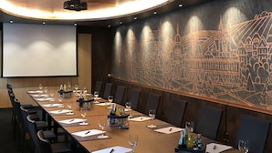 Une salle de conférence équipée d’une longue table, de chaises et d’un écran de projection.