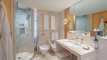 Une salle de bain moderne équipée d’une douche, de deux toilettes, d’un grand lavabo et d’un miroir.