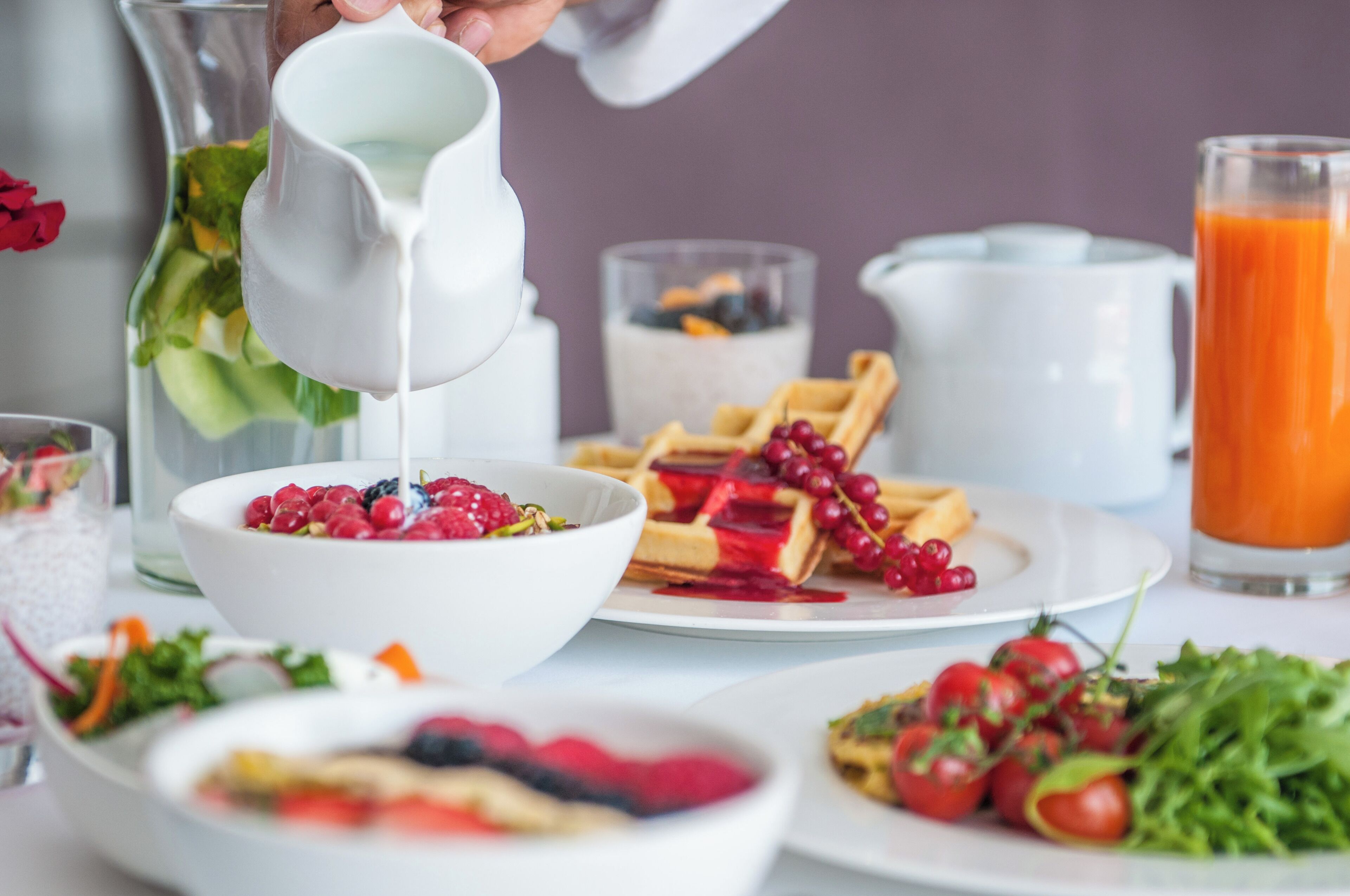 A breakfast setting with a bowl of berries, waffles, and a glass of orange juice.