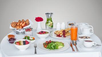 A breakfast table with various dishes, including waffles, a bowl of fruit salad, and a glass of orange juice.