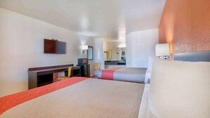A hotel room with a large bed, a desk, a chair, a TV, and a mirror. - Motel 6 Santa Nella, CA - Los Banos (Gustine)