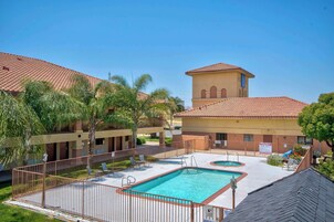 Un hotel con piscina, palmeras y una torre de campanas.