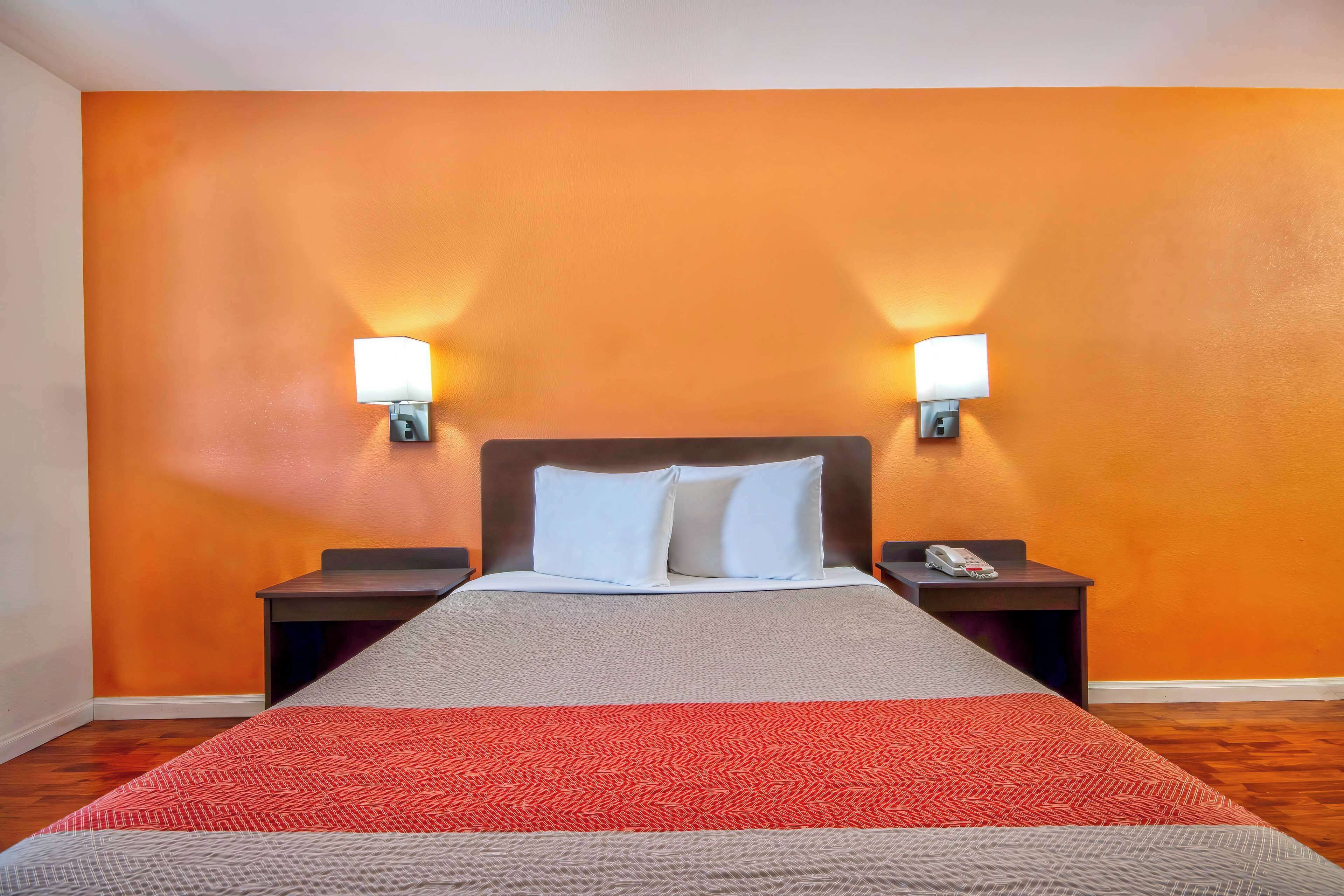 A hotel room with a large bed, two nightstands, and two wall-mounted lamps.