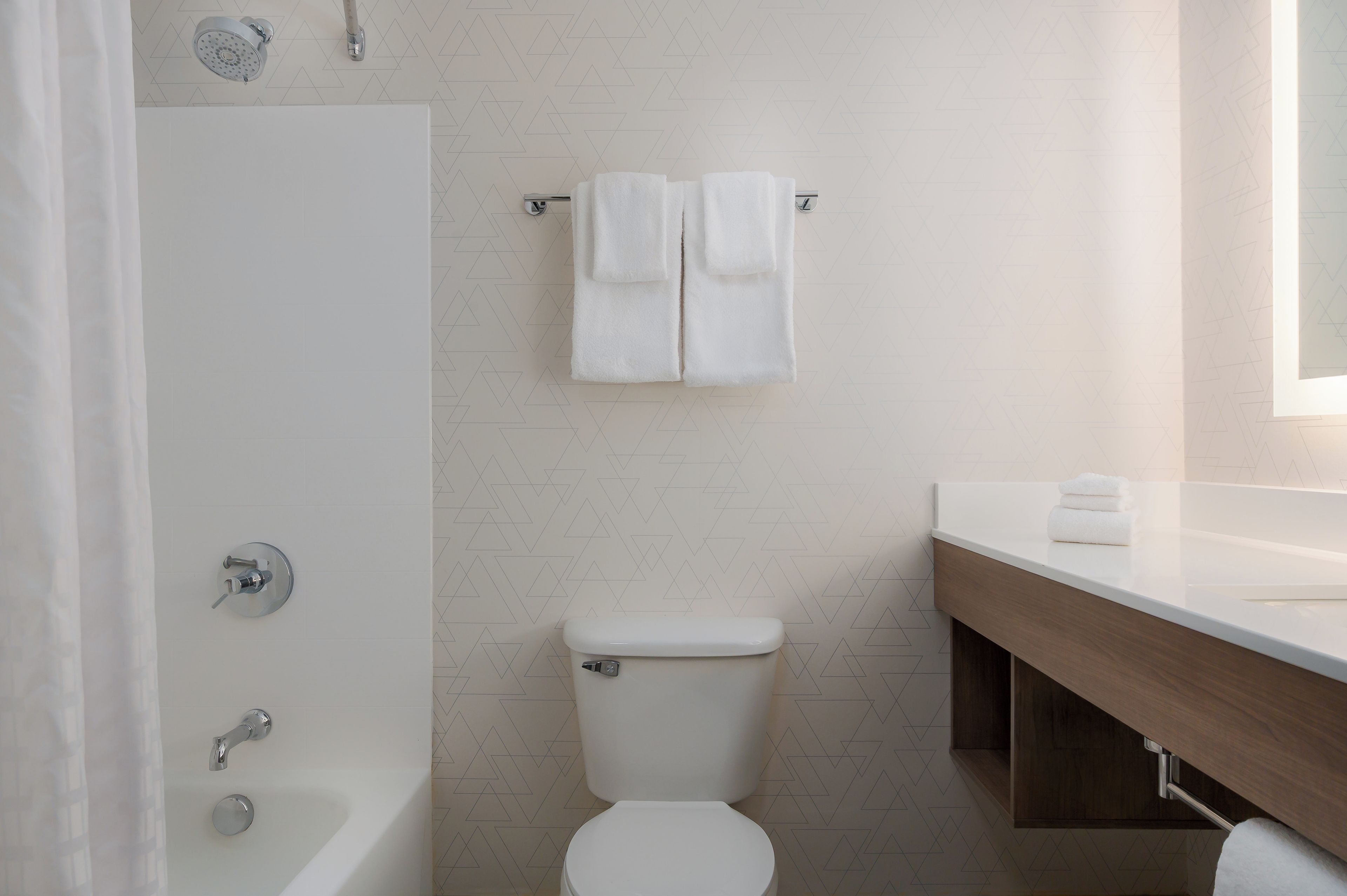 Un baño moderno con bañera, inodoro y tocador con espejo.