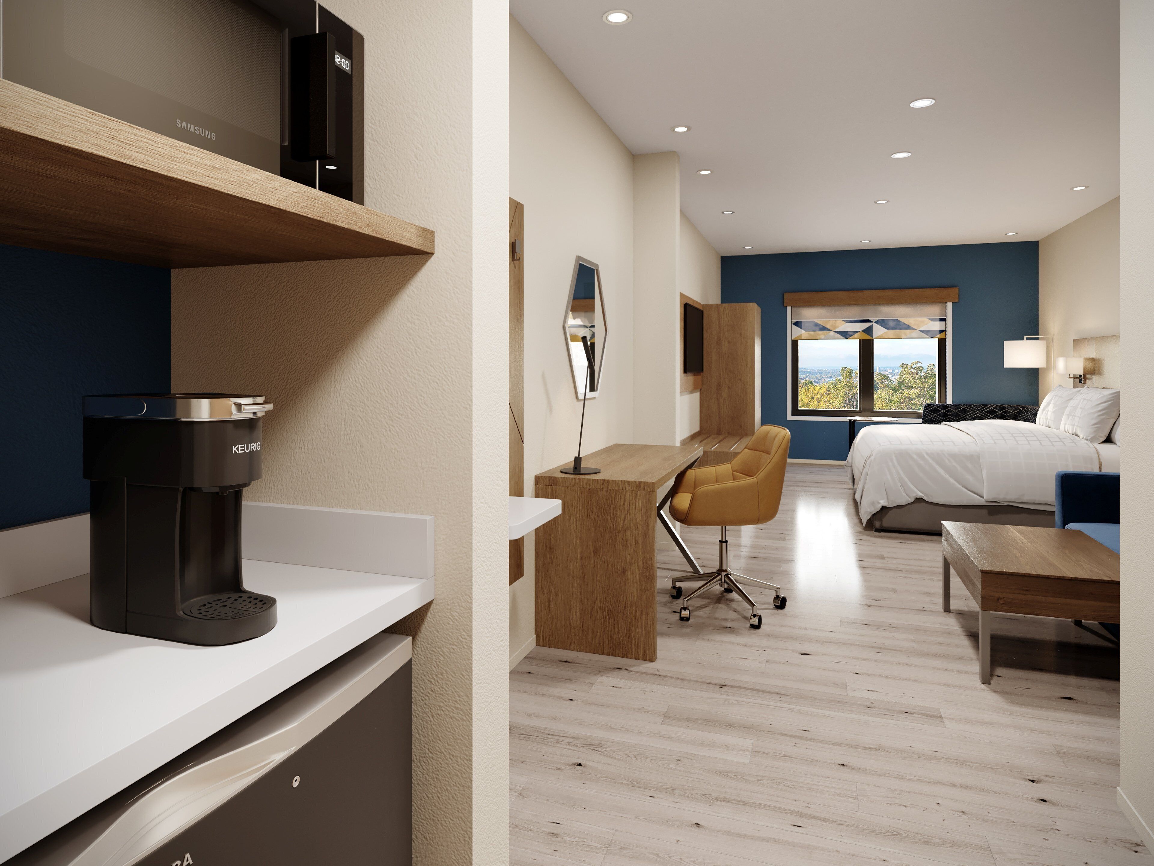 Quarto de hotel moderno com cozinha compacta, uma cama, escrivaninha e vista para o exterior.