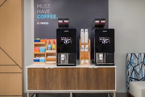 Een koffiehoek met twee espresso machines, een koffieautomaat, en een bord waarop staat 'MUST HAVE COFFEE'.