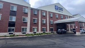 A Holiday Inn Express hotel with a brick facade, multiple windows, and a covered parking area. - Holiday Inn Express & Suites Southfield Detroit by IHG (Southfield)