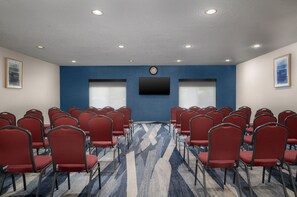A conference room with rows of red chairs, a patterned carpet, and a clock on the wall. - Holiday Inn Express & Suites Southfield Detroit by IHG (Southfield)