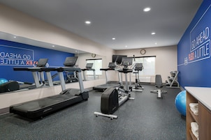 A gym with treadmills, elliptical machines, and exercise balls.