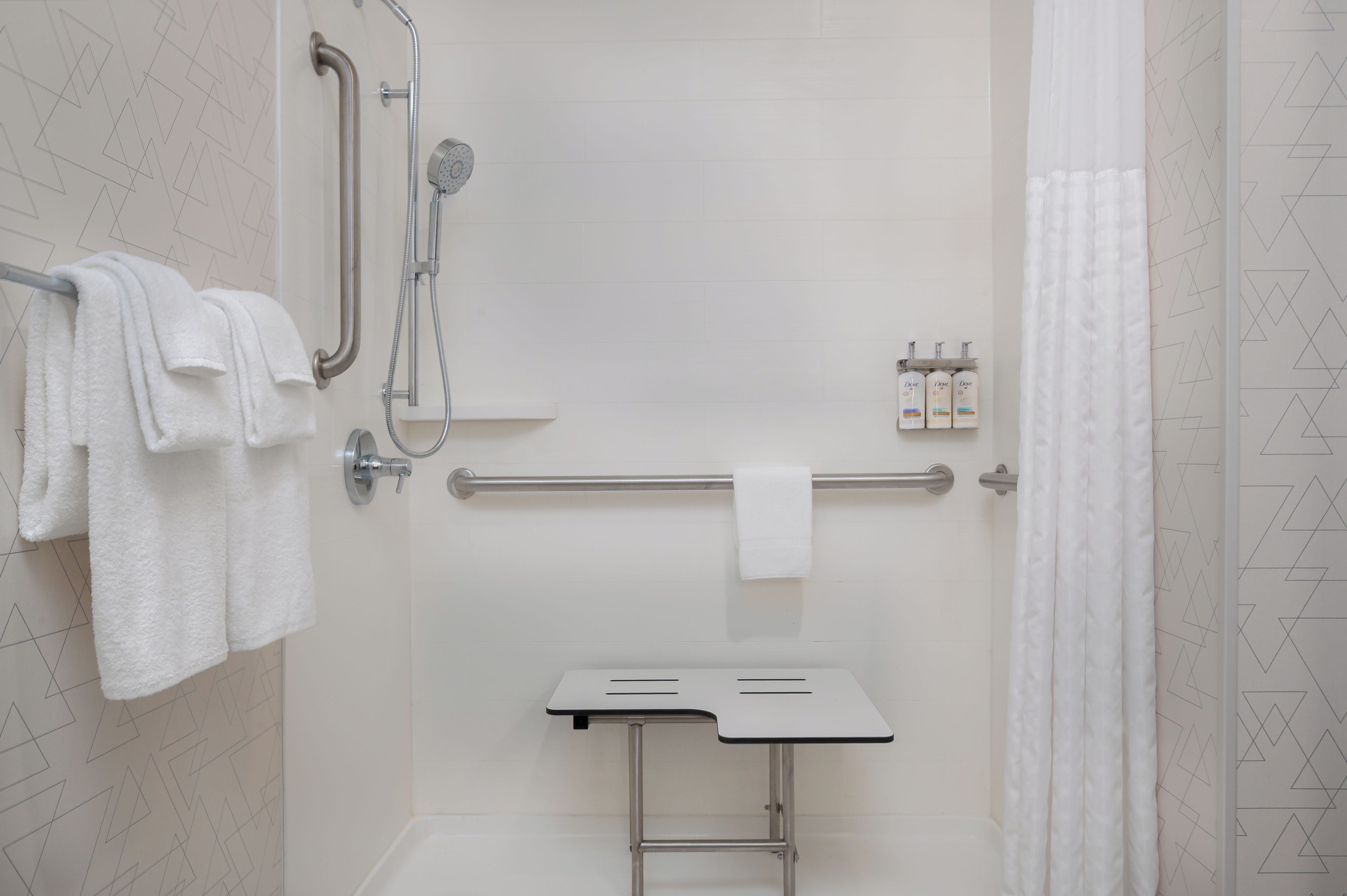 A shower area with a grab bar, a towel rack, and a small table with toiletries.