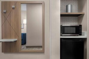 A modern kitchen with a microwave, a dishwasher, and a wooden cabinet with a sliding door.